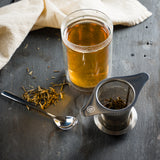 tea infuser basket and tea in a double-wall glass tumbler